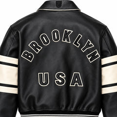Close-up rear view of Avirex Brooklyn USA black leather jacket showing appliqué-style lettering and textured leather finish