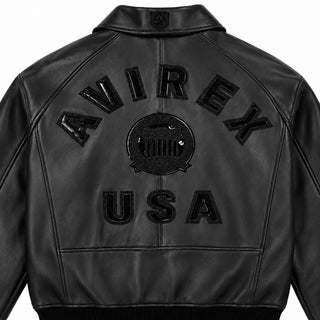 Close-up back view of Avirex black tonal leather bomber showing glossy AVIREX lettering, heritage crest and USA logo