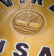 Close-up rear detail showing tonal Timberland tree emblem and contrasting AVIREX USA appliqué on tan leather