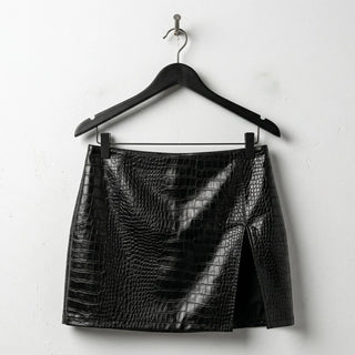 Front view of black croc embossed mini leather skirt with side slit
