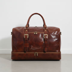 front view brown leather drop bottom duffle bag with buckles and front zip pocket by Leather Unit.