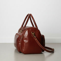 side view brown leather travel duffle showing exterior pocket detail.