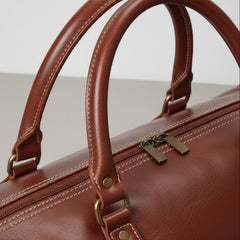 close up of brown leather duffle bag handles and metal hardware.