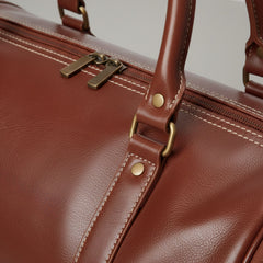 close up of zipper and stitching on brown genuine leather travel bag.