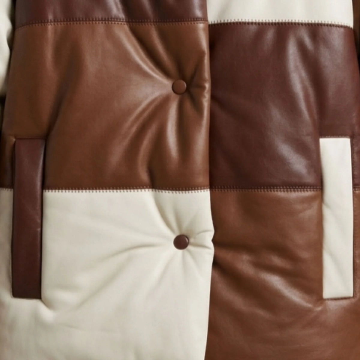 Close-up of patch pocket and tufted texture on brown leather puffer jacket