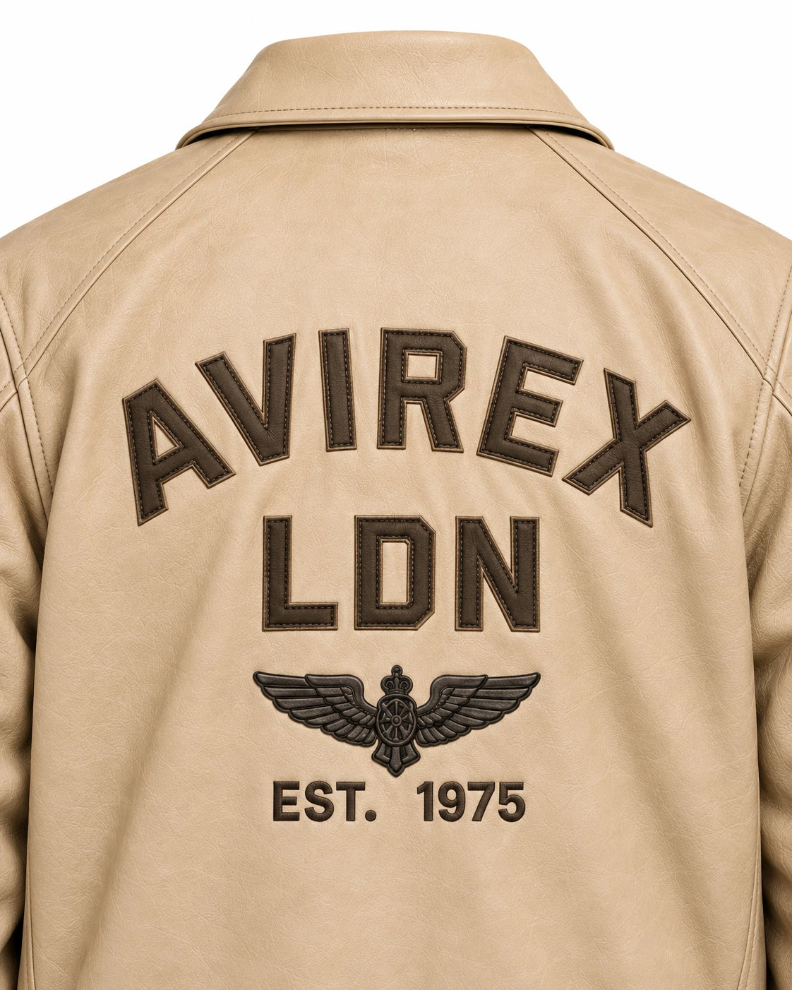 Close-up of cream aviator jacket back showing raised brown lettering, winged aviation emblem and 1975 detail