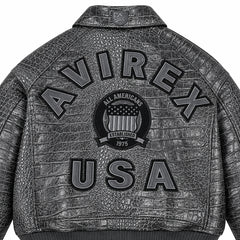 Close-up of grey crocodile-textured leather jacket back showing raised USA lettering and central shield emblem