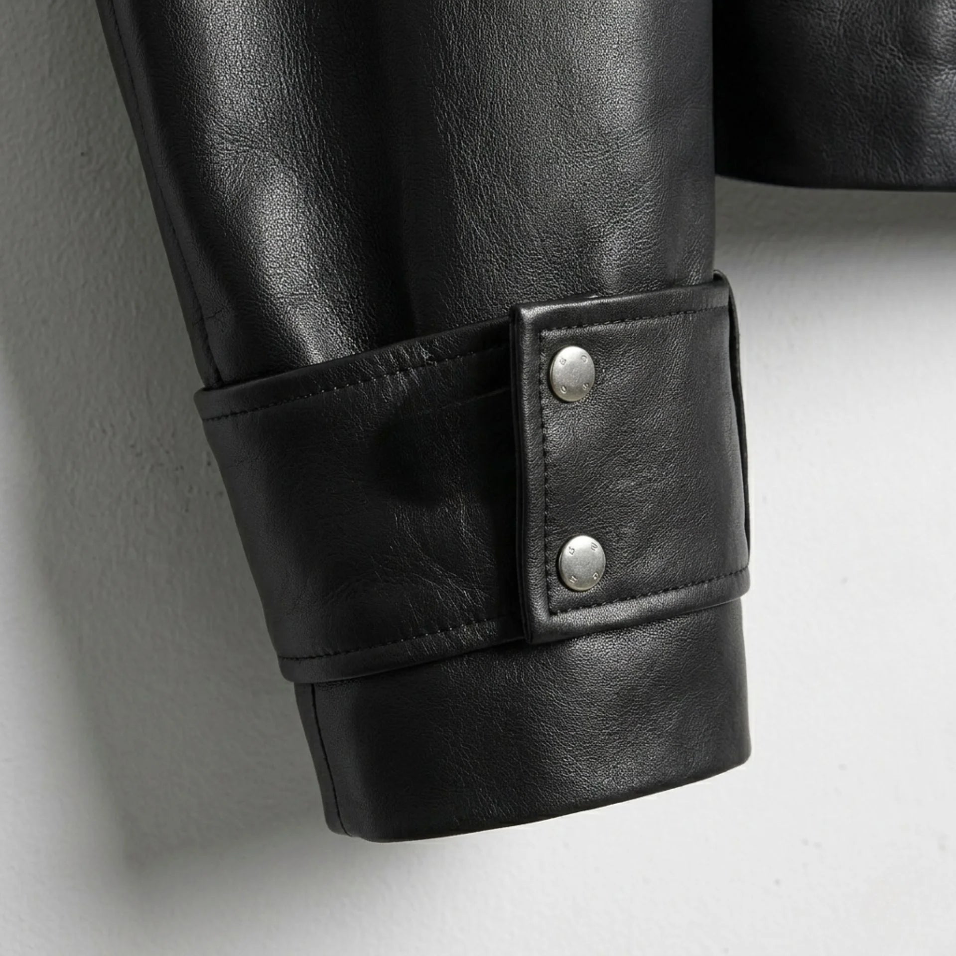 Close up of wide cuff strap with snap buttons on black leather jacket