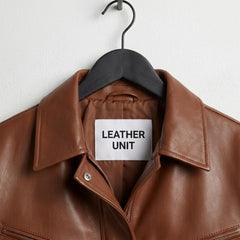 Close up of Leather Unit label on women’s brown leather bomber jacket
