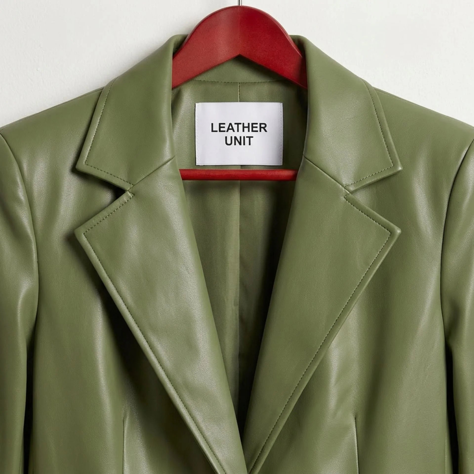 Close up of notched lapels and Leather Unit label on green leather blazer