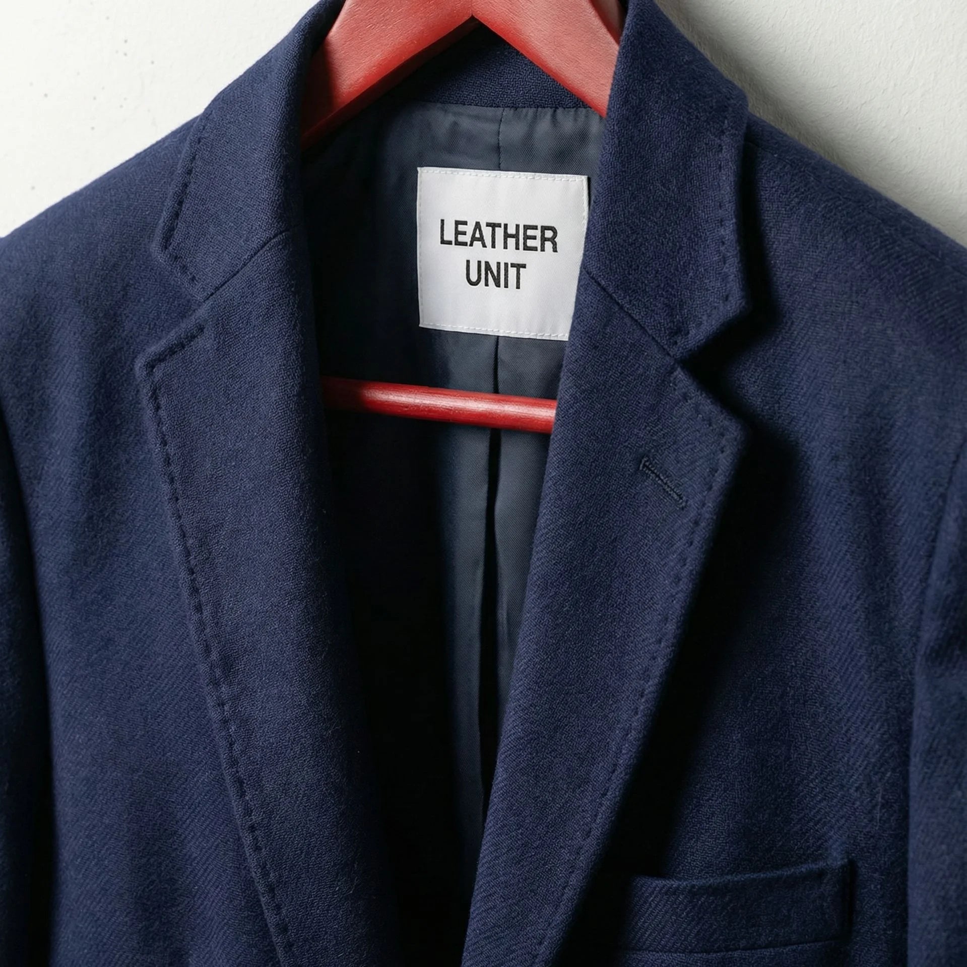 Close up of notch lapels and Leather Unit label on navy blazer