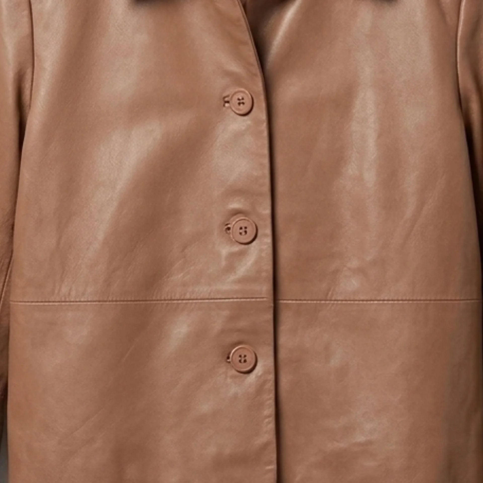 Close-up of button front detail on a women's tan cropped leather shirt jacket
