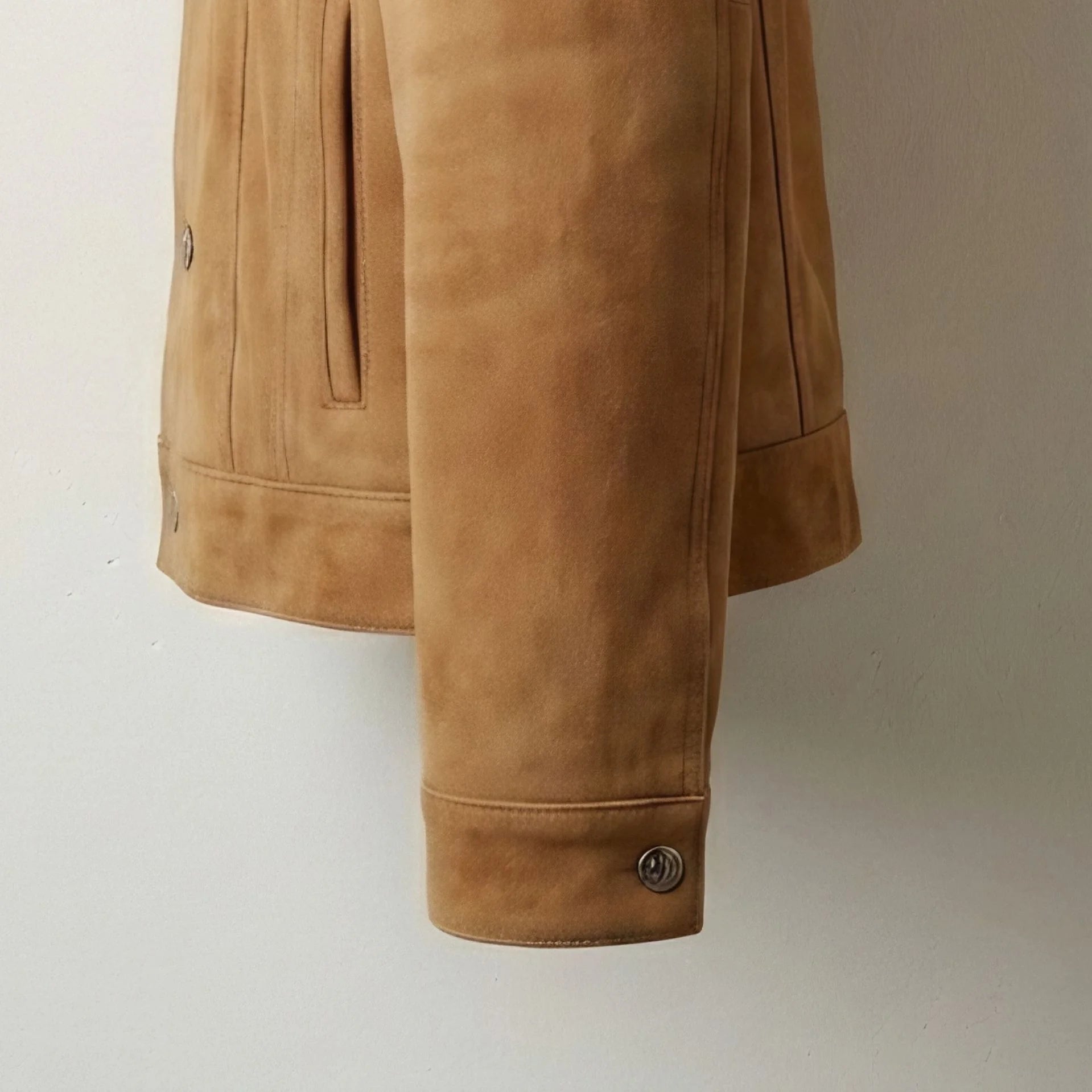 Cuff and sleeve detail on men's tan suede trucker jacket with button closure