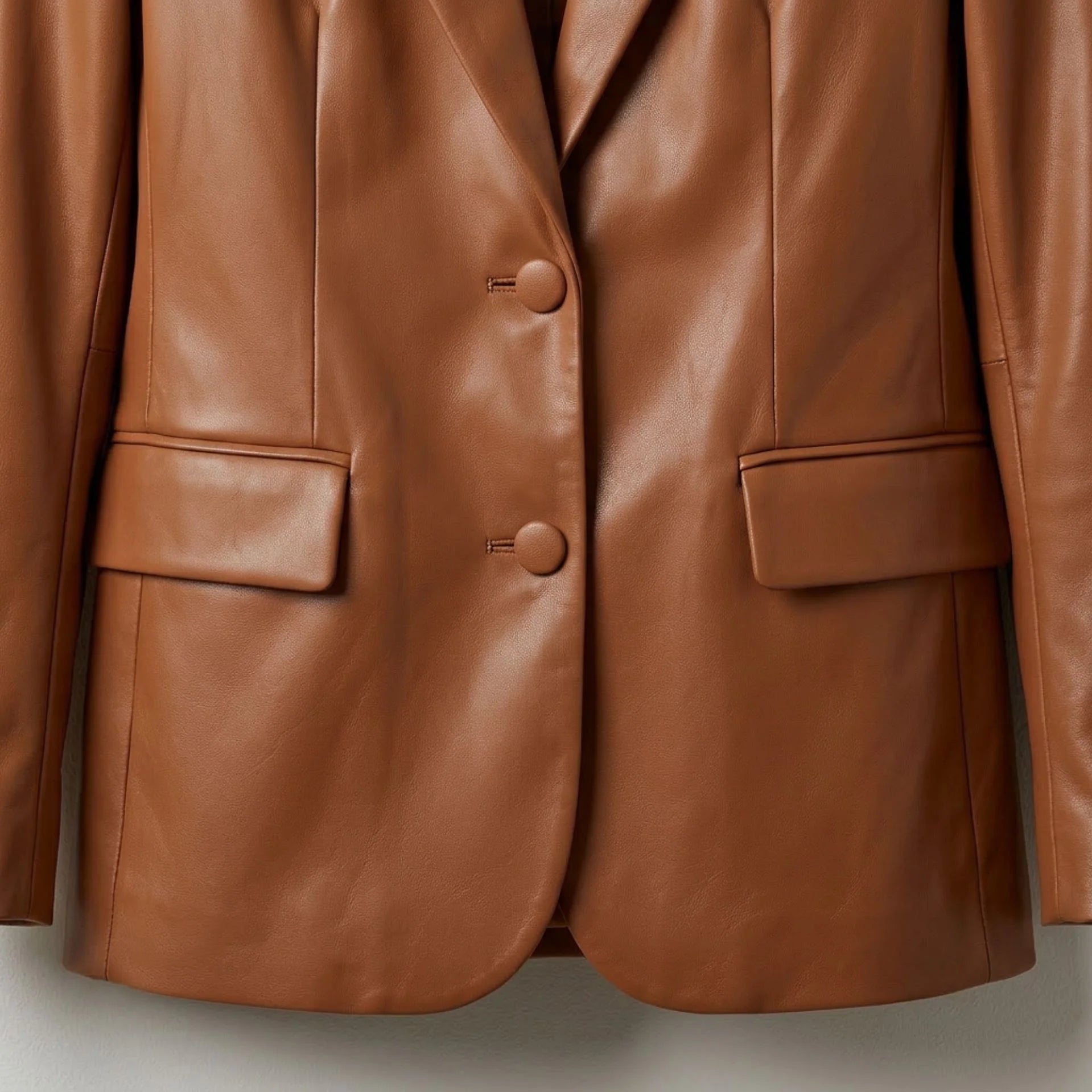Two button front and flap pockets on women’s cognac brown leather blazer