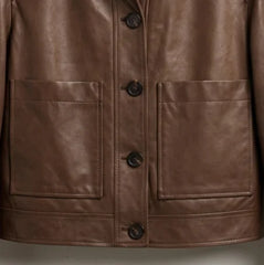 Front patch pocket and button closure detail on women’s dark brown leather jacket