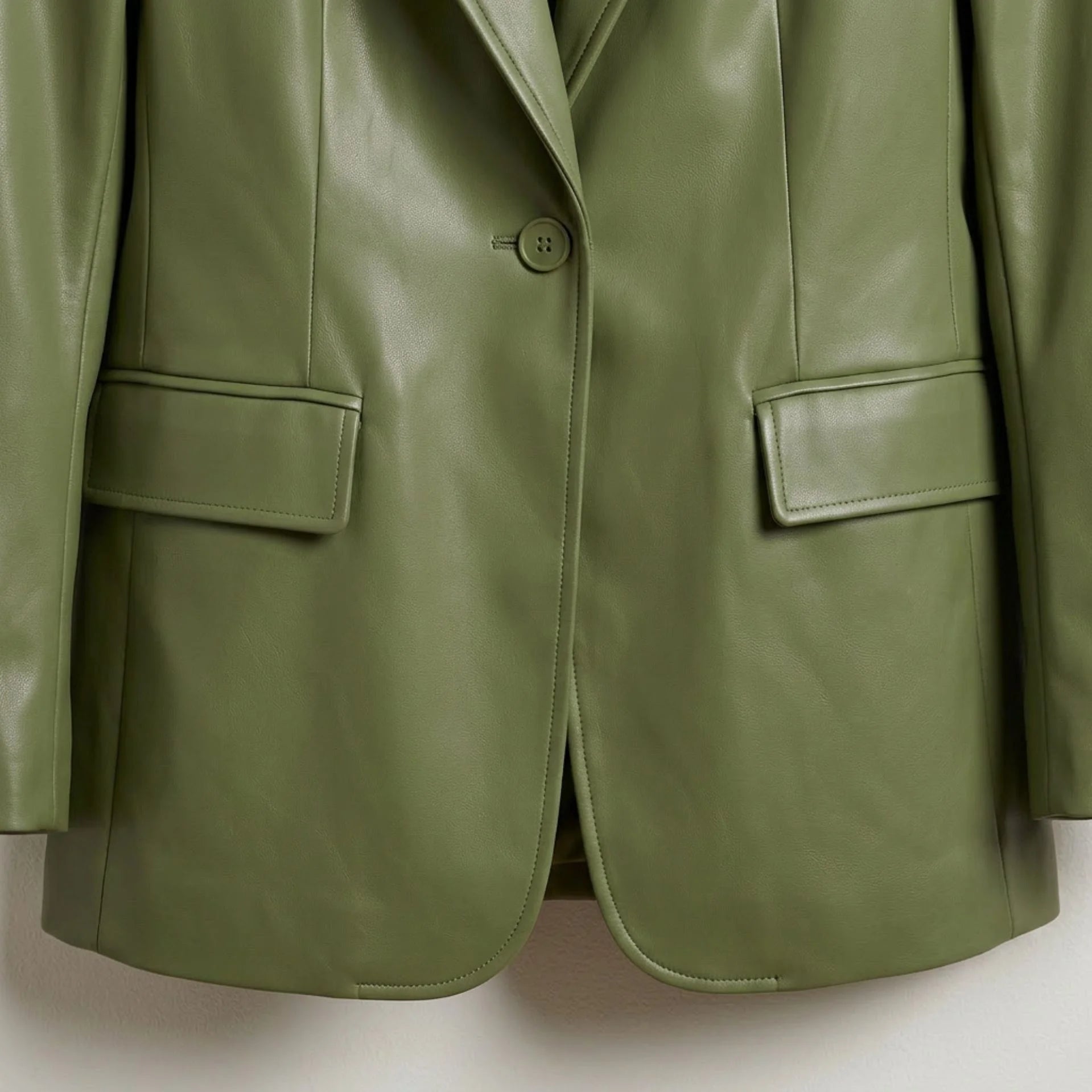 Single button front and flap pockets on women’s green leather blazer