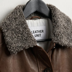Shearling sherpa collar and Leather Unit label on women’s brown leather jacket