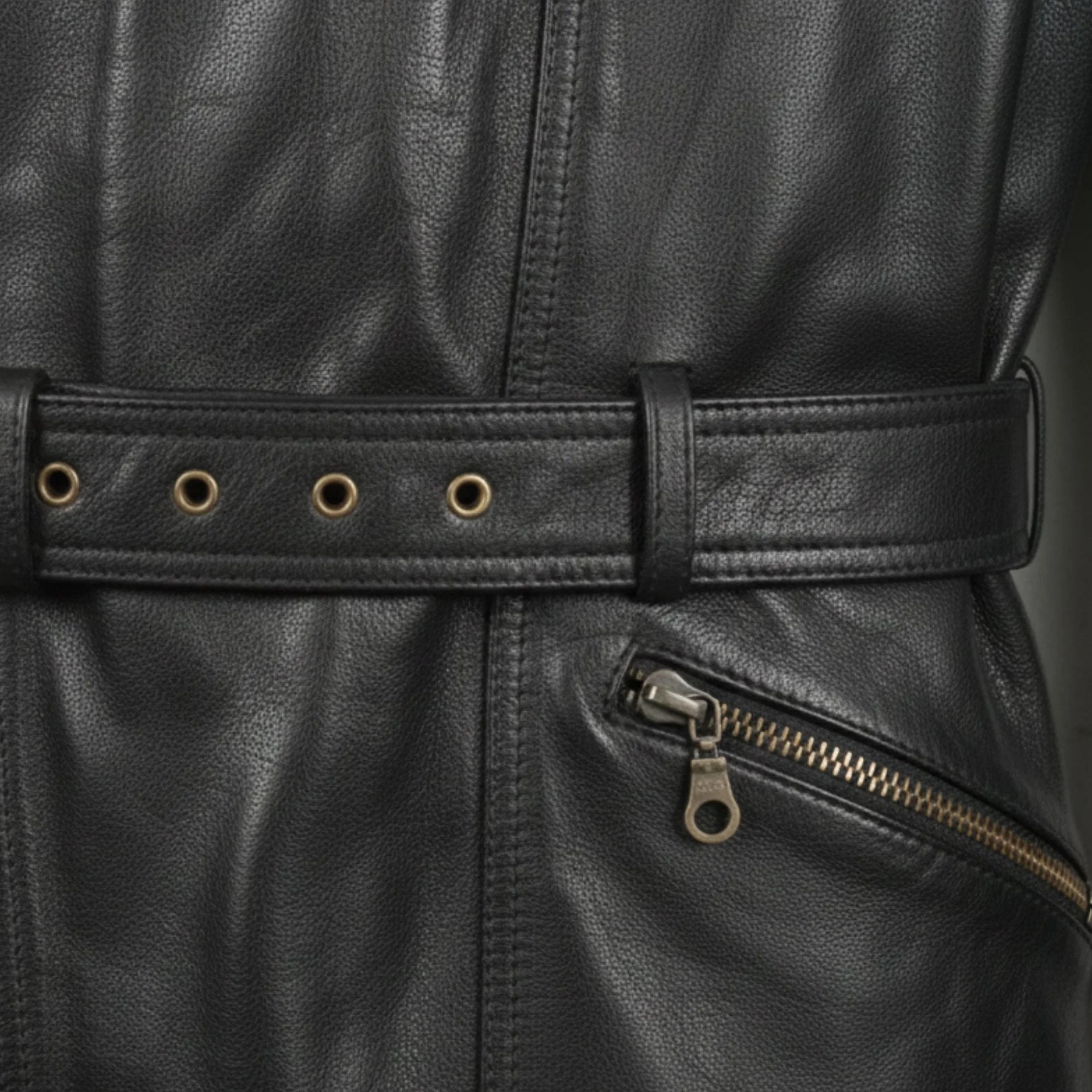 close up belted waist and brass zipper pocket on mens black leather motorcycle coat.