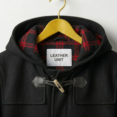 Close up of hood with red plaid lining and Leather Unit label on black duffle coat.
