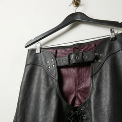 Close-up of waist belt, rivets and burgundy pants under men's black leather chaps