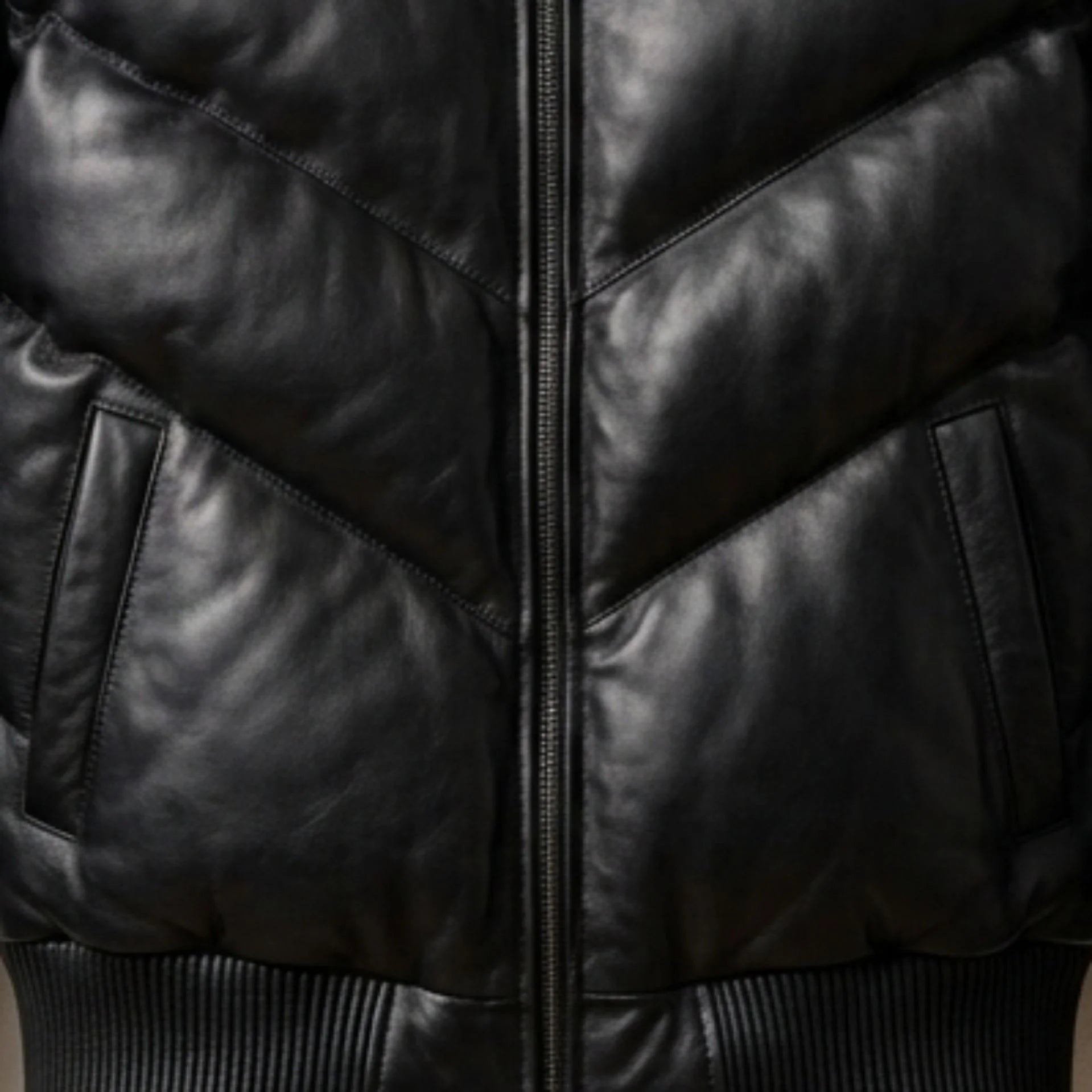 Close-up of functional pockets and heavy-duty zipper on black puffer leather jacket