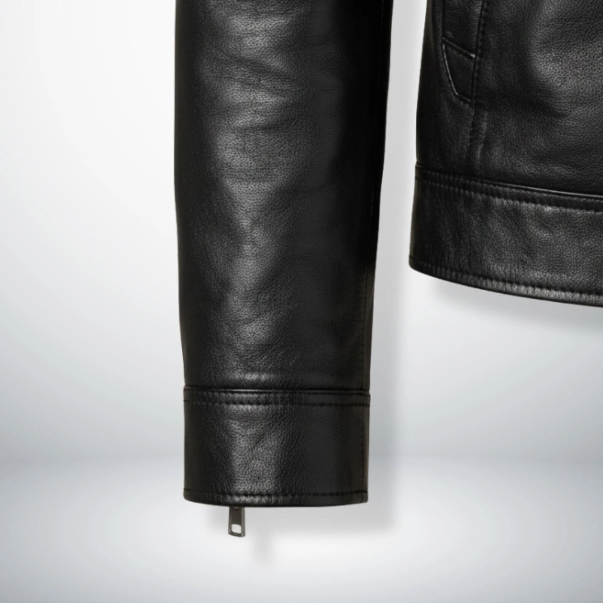 Detail of zippered cuff and hem stitching on men's black genuine leather biker jacket.