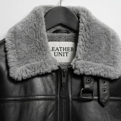 close up grey shearling collar and buckle throat latch on black leather jacket.