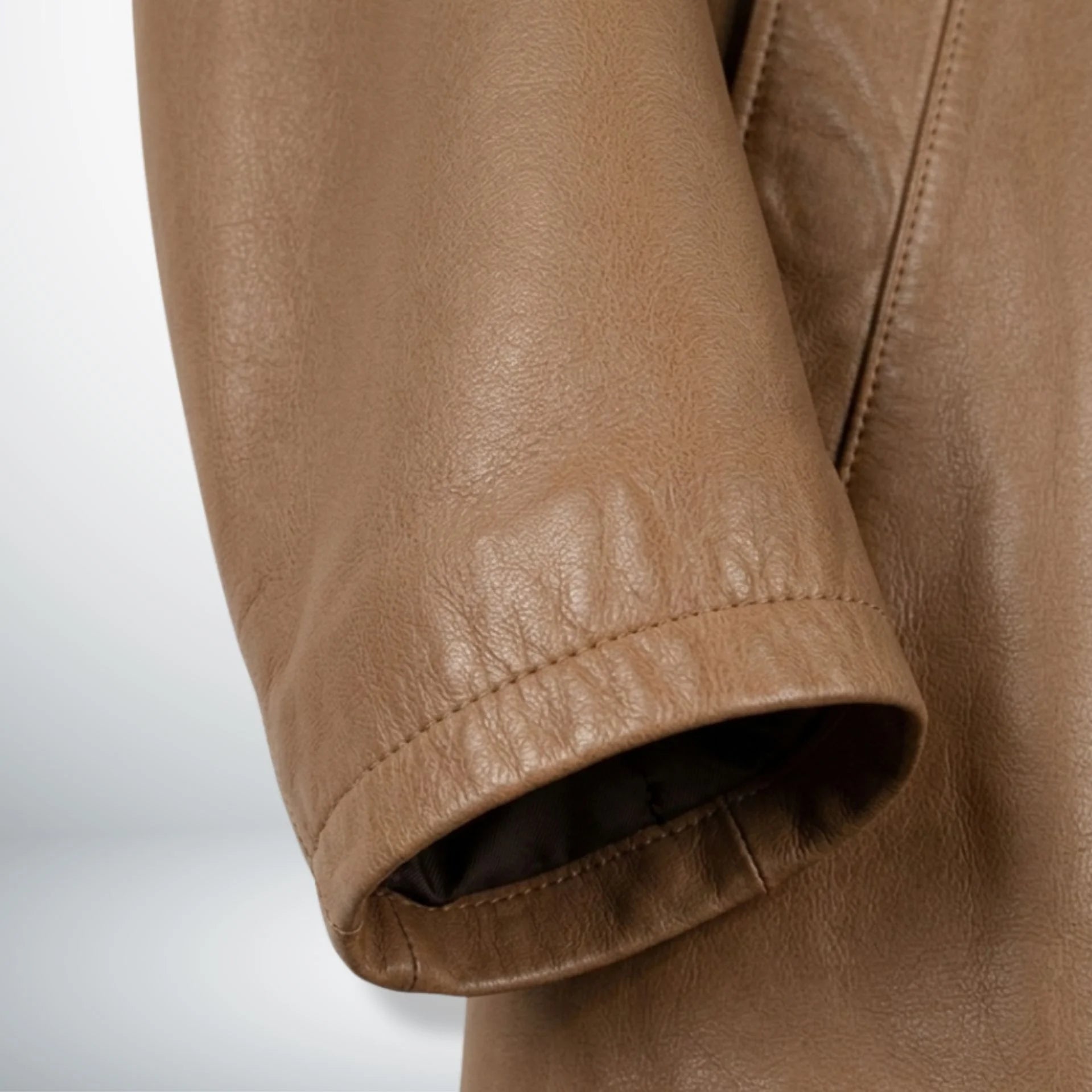 Detail of sleeve cuff and leather texture on men's camel brown coat.