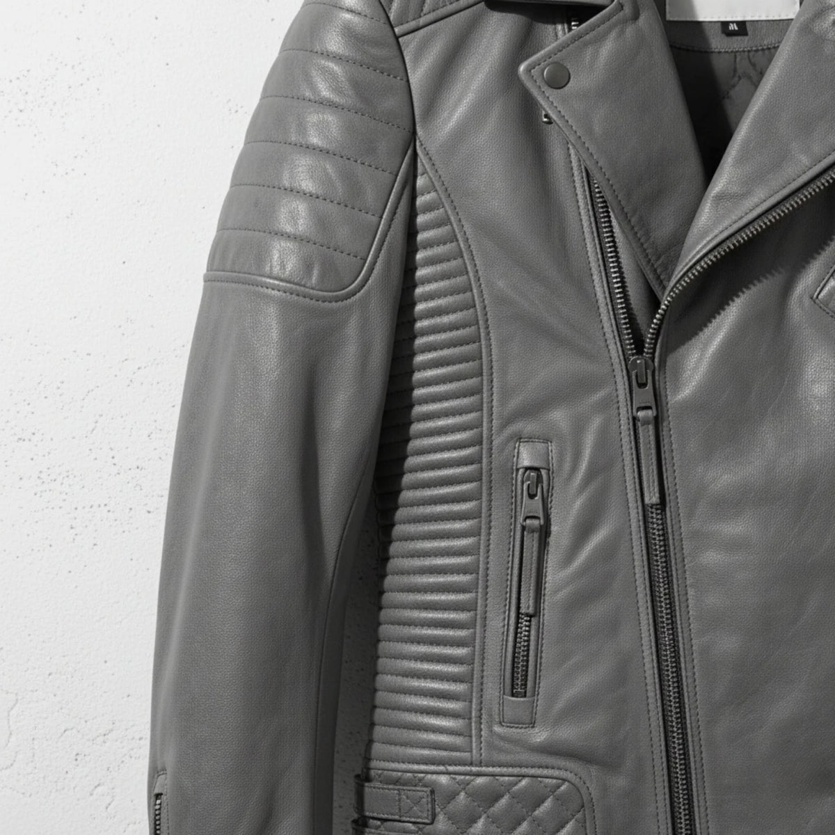 detail of ribbed side panel and zipper pocket on men's grey quilted moto jacket.