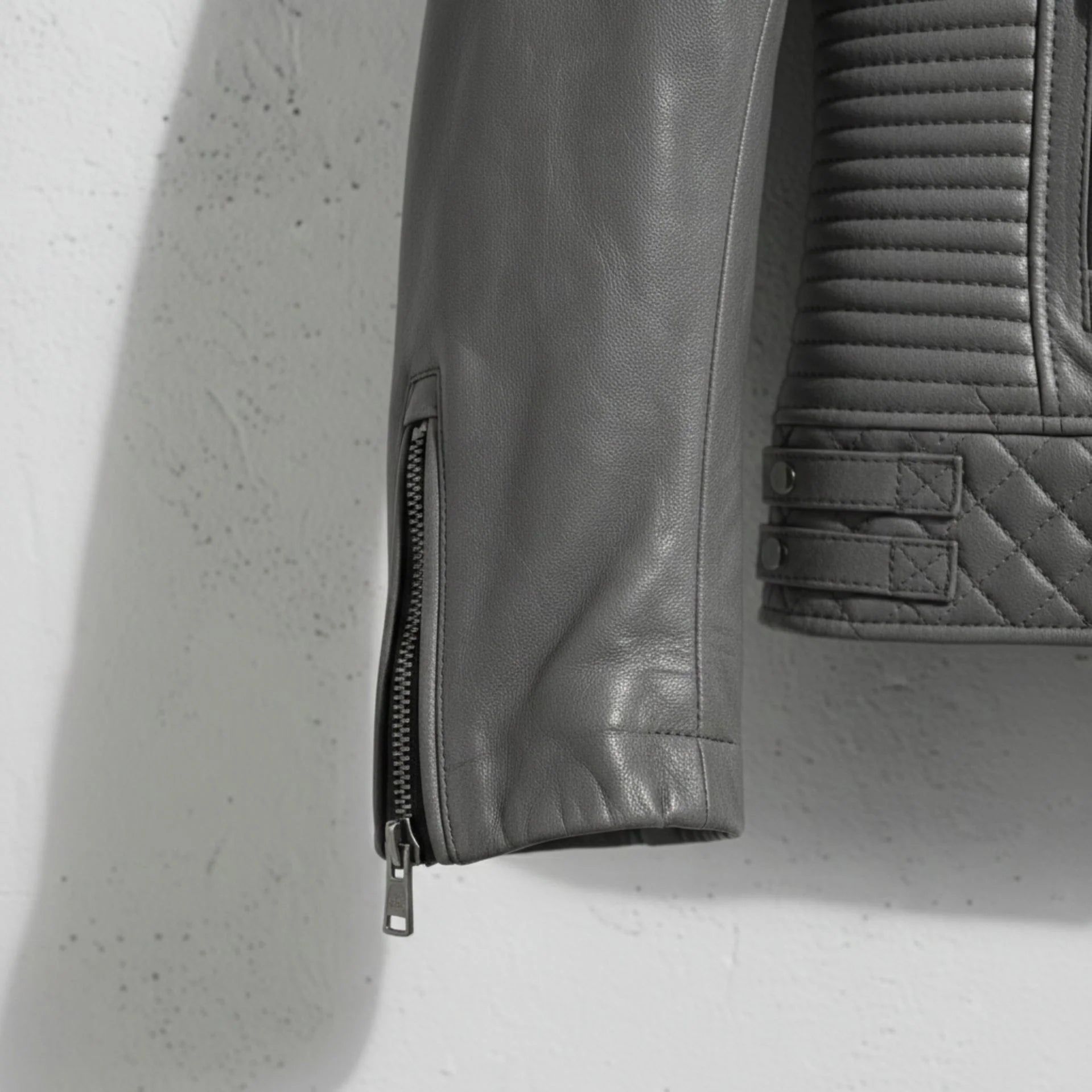 sleeve and cuff zipper close up on men's grey leather motorcycle jacket.