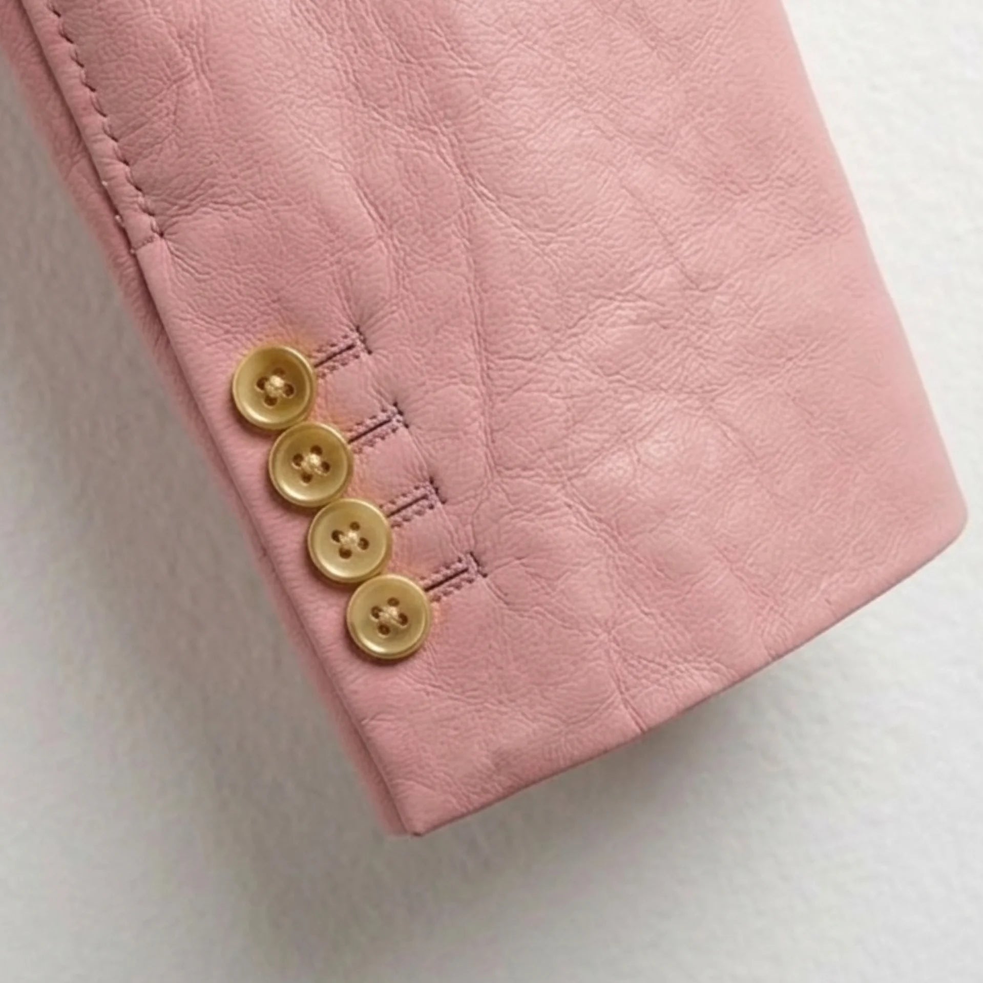 Gold cuff buttons detail on men’s light pink leather blazer sleeve