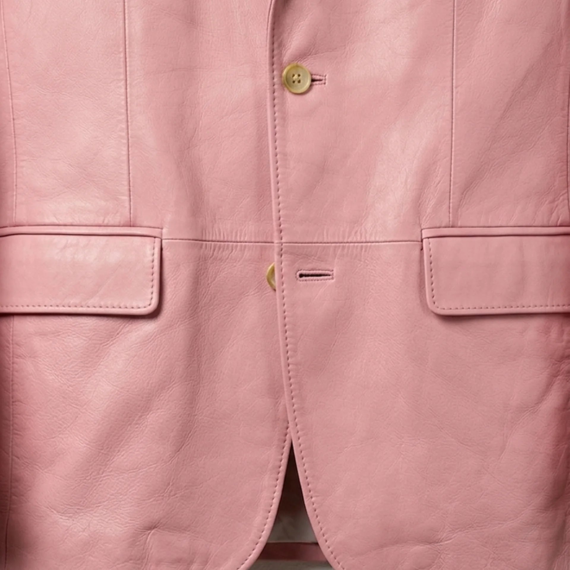 Flap pocket and front button close up on men’s pastel pink leather blazer