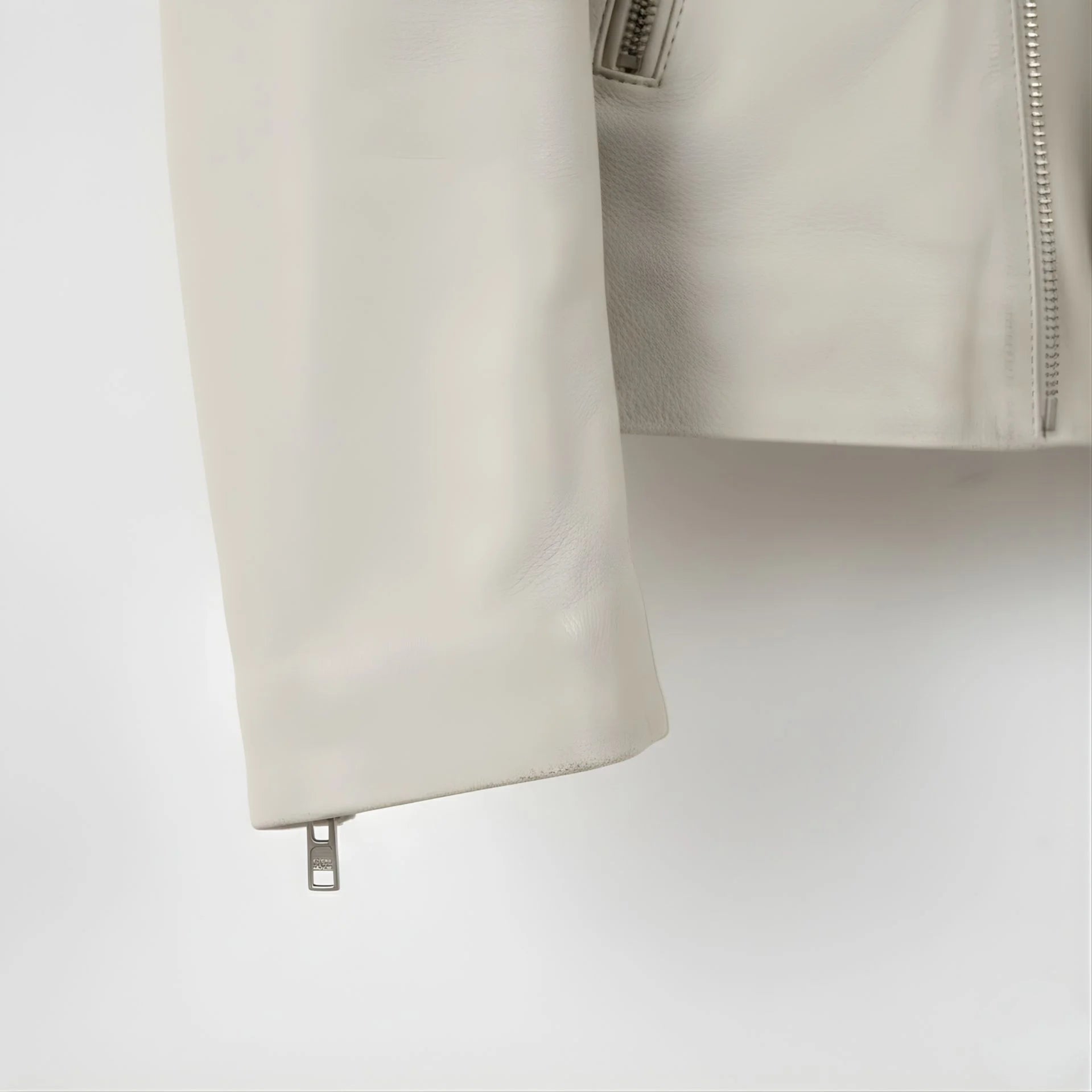 sleeve and cuff zipper close up on men's off white leather biker jacket.