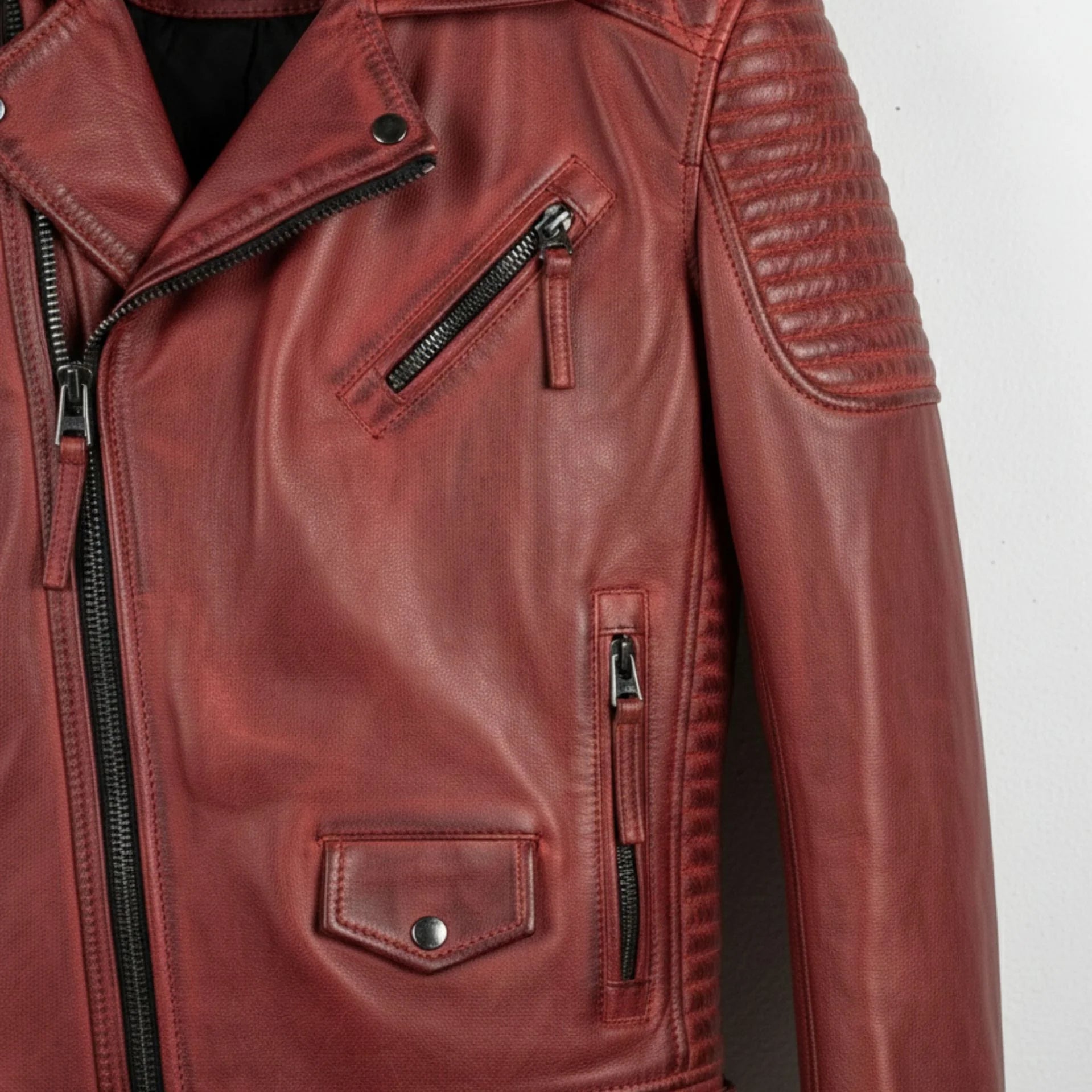 detail of zip pockets and flap pocket on men's red leather biker jacket.