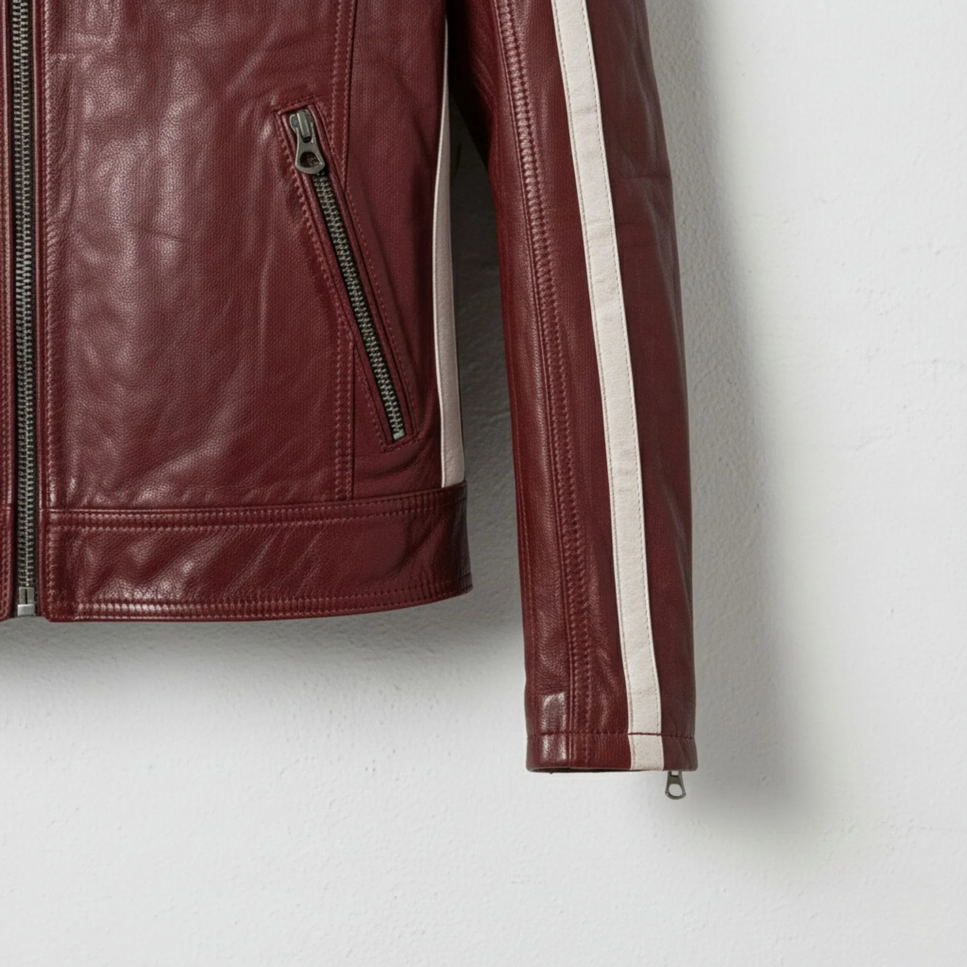 Detail of sleeve stripe and zip pocket on men's red cafe racer jacket.