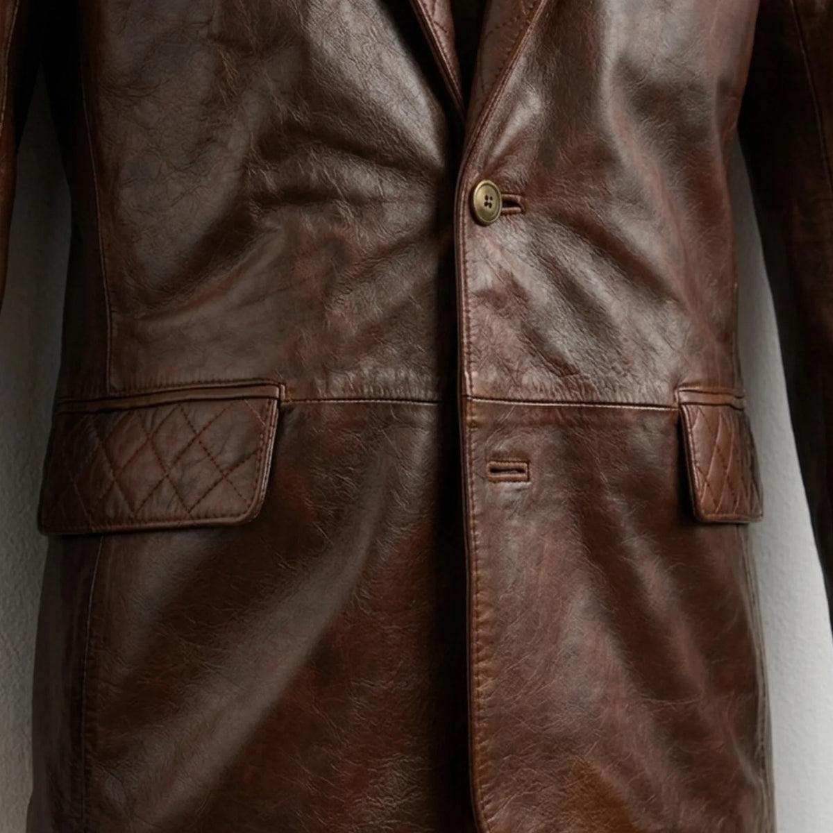 Front button and quilted pocket flap close up on men’s brown leather blazer jacket