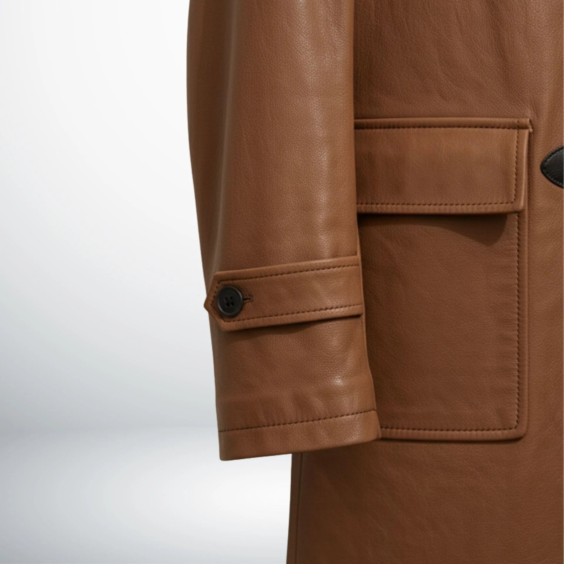 Detail of cuff strap and front flap pocket on men's tan leather hooded coat.