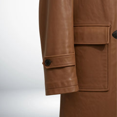 Detail of cuff strap and front flap pocket on men's tan leather hooded coat.