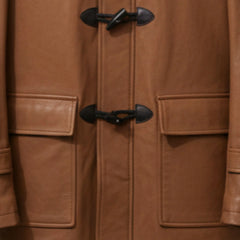 Close up of toggle fastenings and pockets on men's tan leather duffle coat.