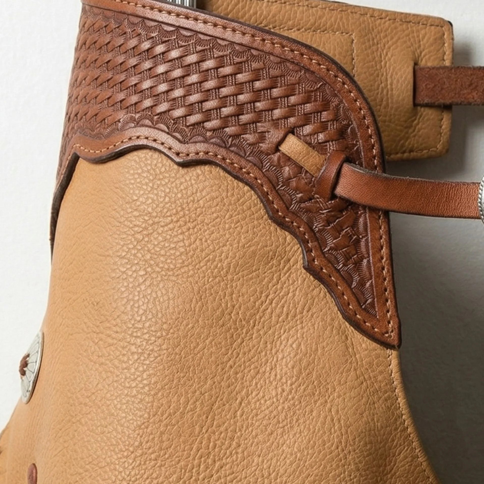 Close-up of basket-weave tooling and stitching on brown yoke of western chaps
