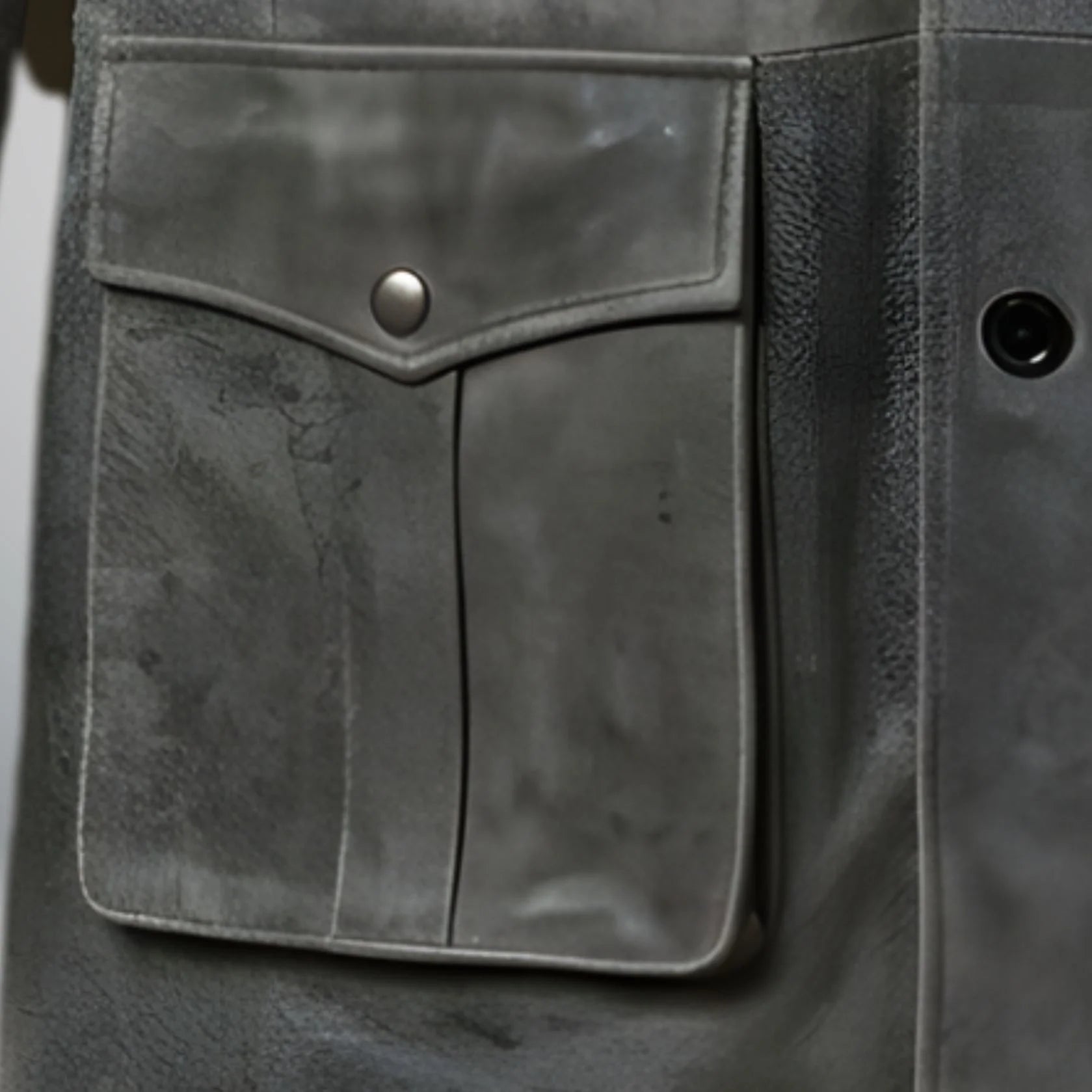 close up lower front flap pocket with snap on mens grey leather coat.