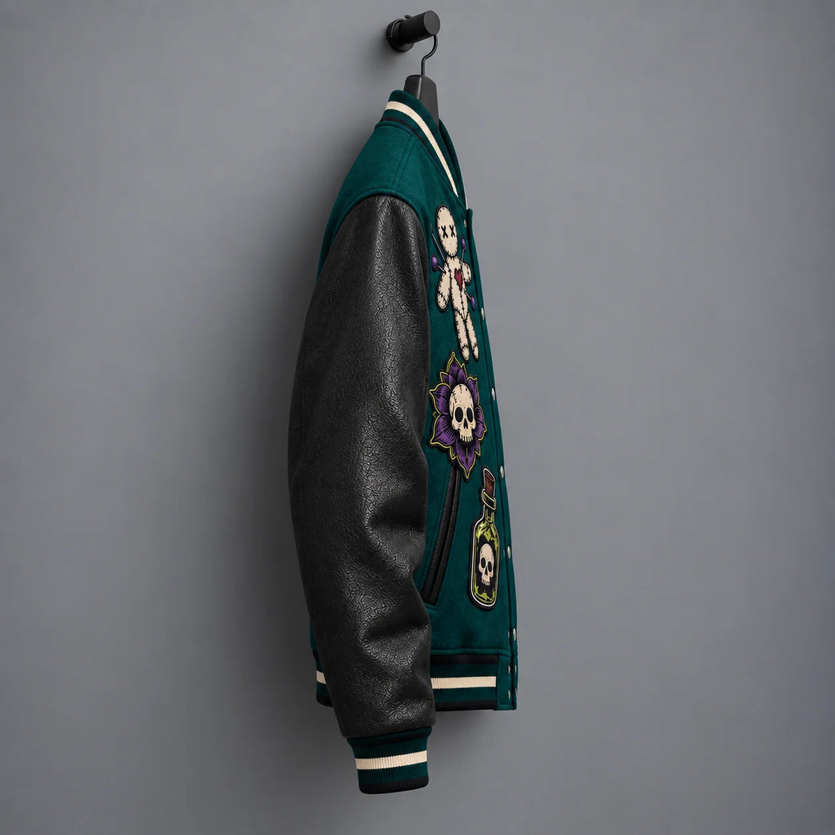 Side profile of deep teal varsity jacket highlighting textured black genuine leather sleeve and embroidered front