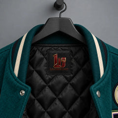 Close-up of striped varsity collar, black quilted lining and Voodoo Bloom interior label on deep teal jacket