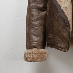 Close-up of brown leather sleeve with rolled shearling cuff on women’s jacket