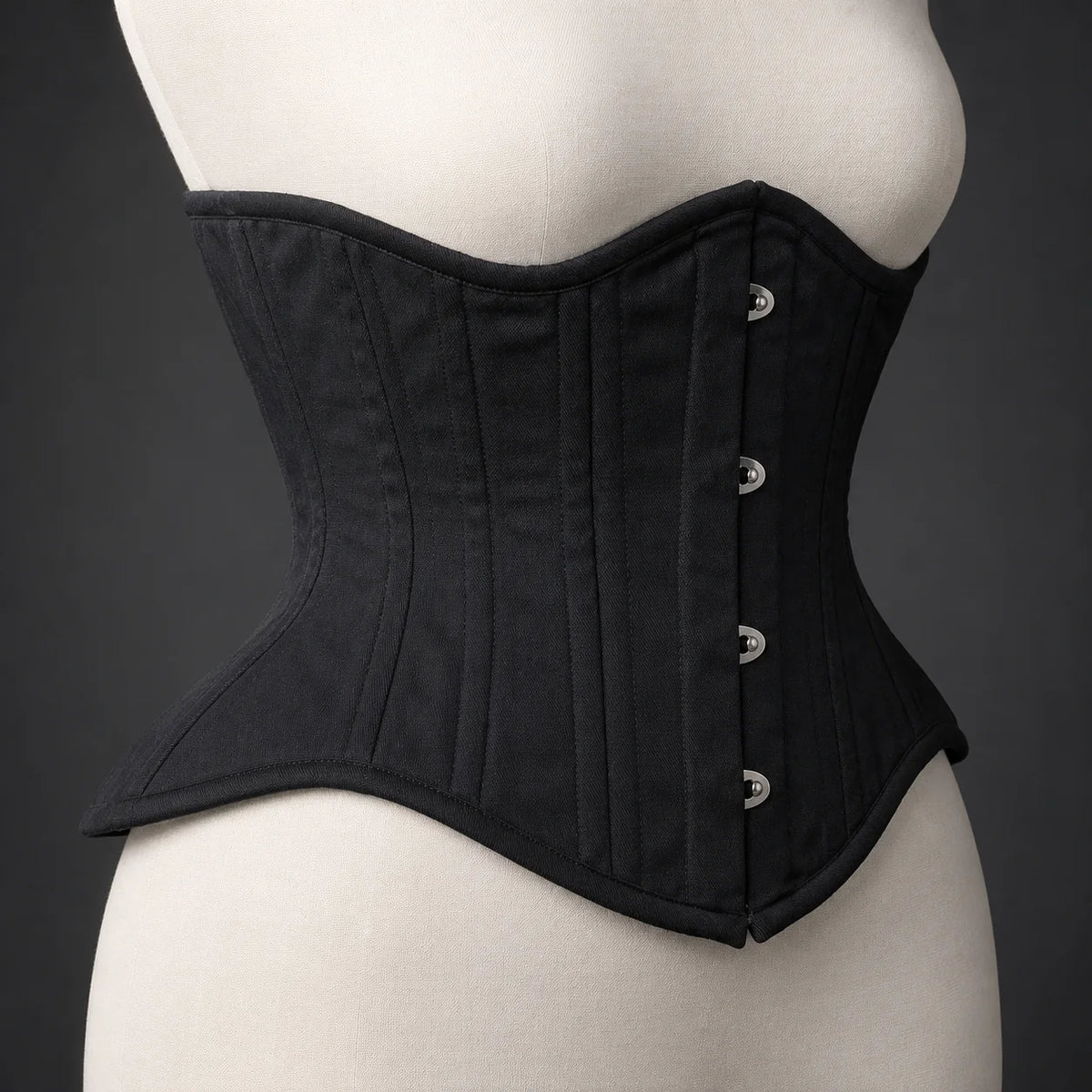 Side profile of black underbust corset showing structured waist shaping, curved upper edge and flared lower panels