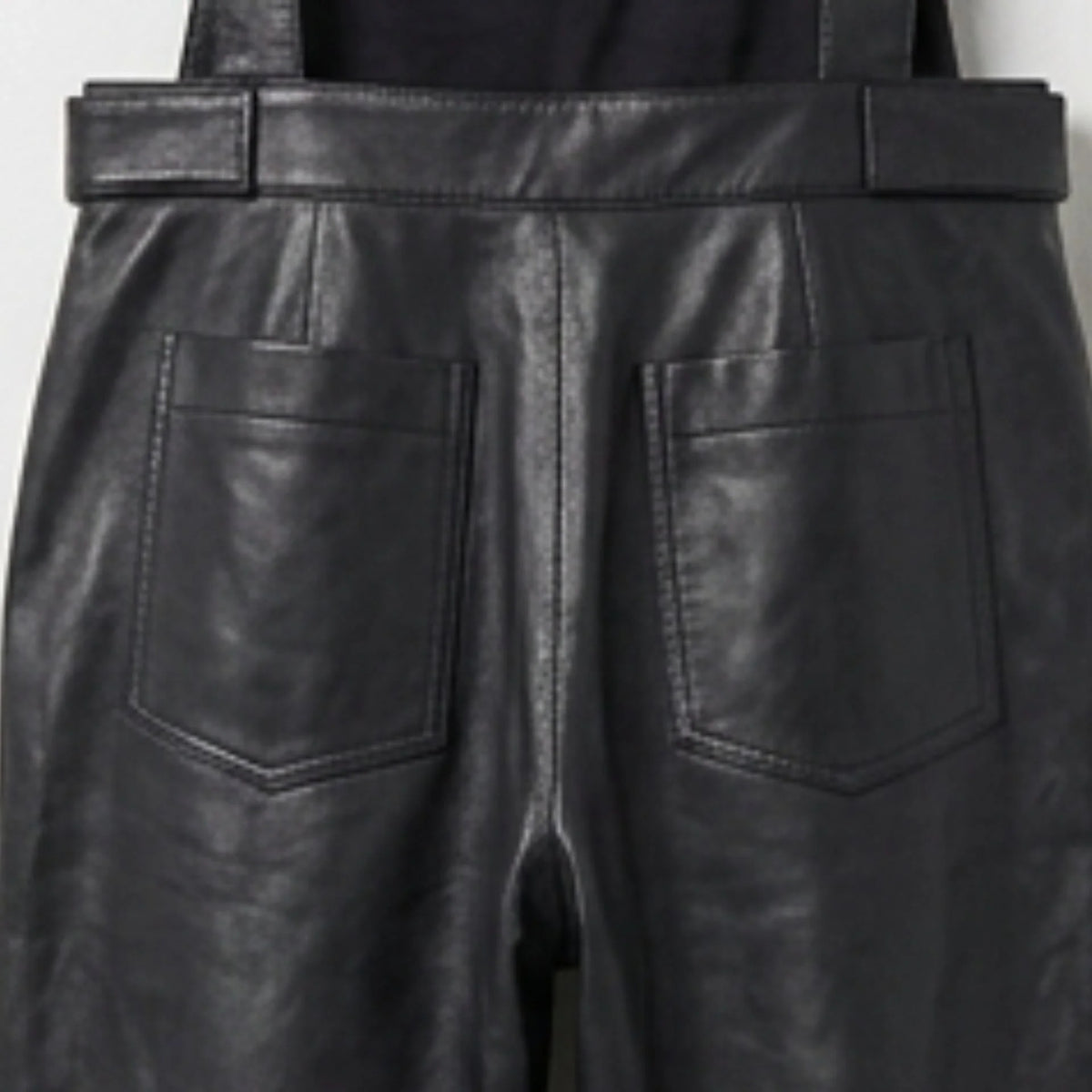 Close up of back patch pockets on black leather overalls
