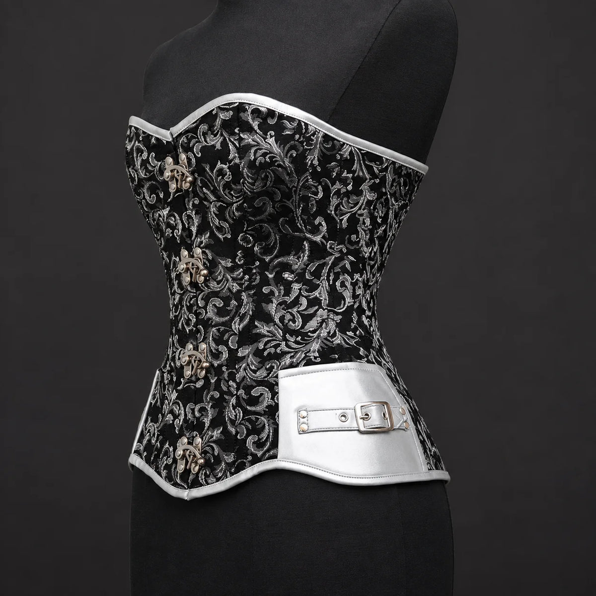 Three-quarter product view of black silver corset highlighting silver faux leather side panel and buckle accent