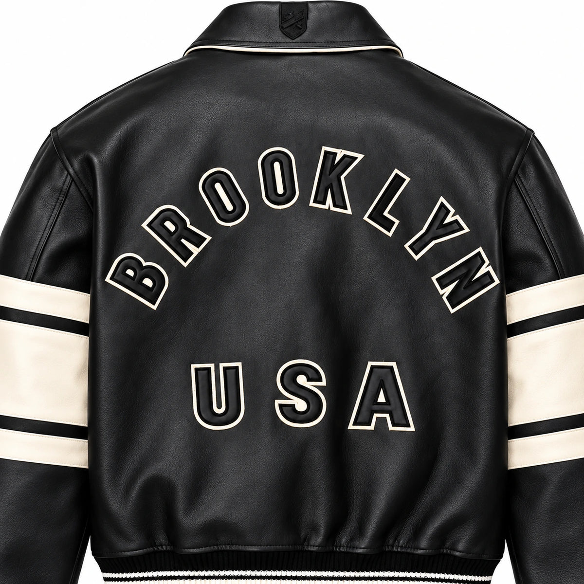 Close-up rear view of Avirex Brooklyn USA black leather jacket showing appliqué-style lettering and textured leather finish