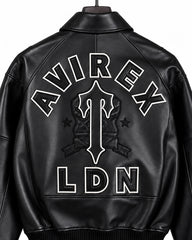 Close-up rear detail of Avirex black leather bomber showing AVIREX lettering, outlined central emblem, stars and LDN logo