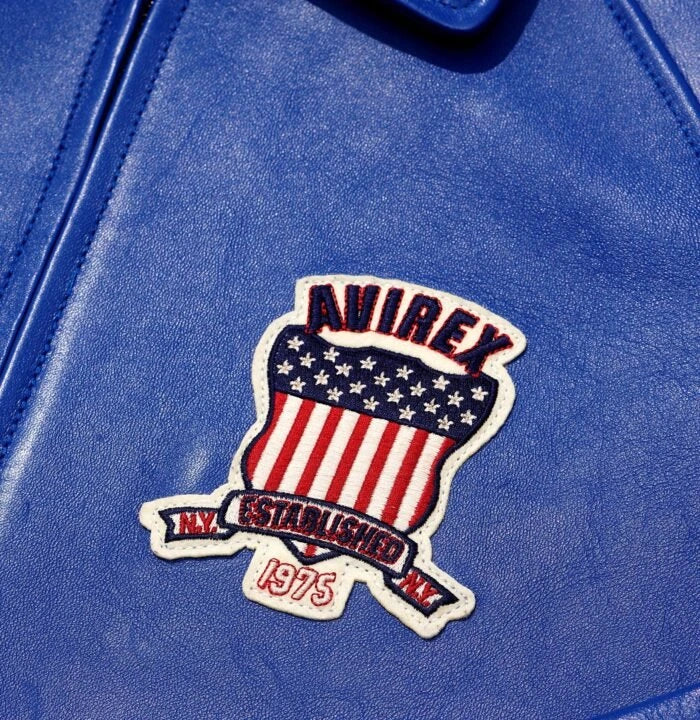 Close-up of blue Avirex leather jacket showing Established 1975 American shield chest patch and leather texture